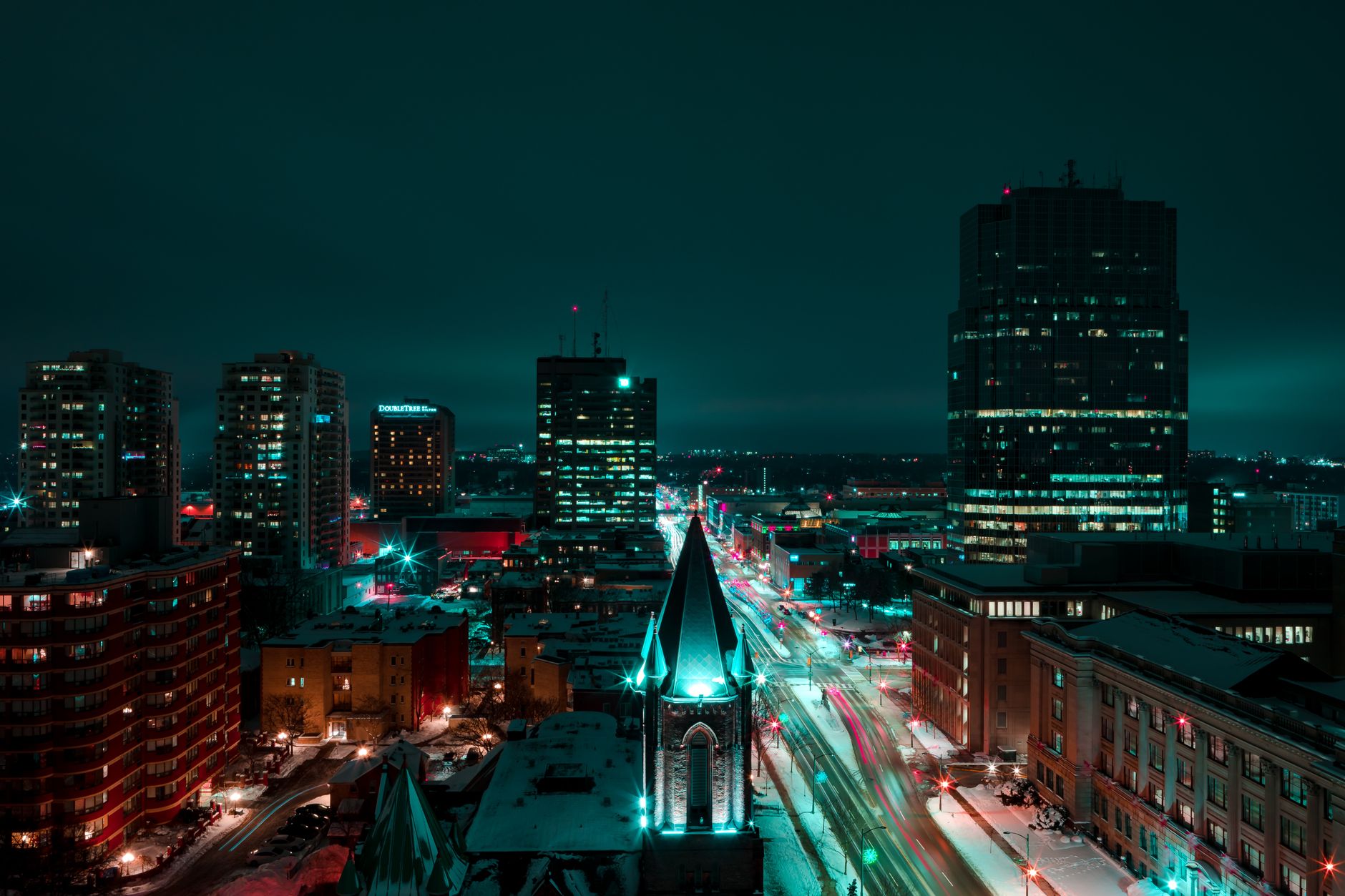 A nightscape of downtown London in the winter with lighting illuminating buildings and snowy streets.